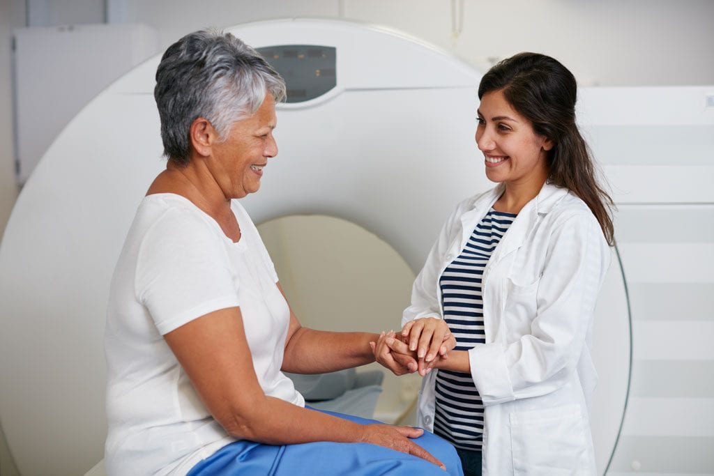 A woman seems at ease as a technologist prepares to give her a CT scan.